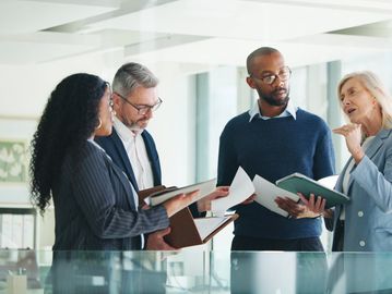 Four professionals discussing documents in an office.