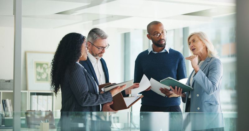 Business, documents and people with meeting discussion for finance trends, policy decision or update. Financial managers, report and feedback in office for investment strategy or risk management team