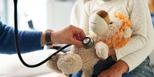 Doctor checking a child's stuffed toy with a stethoscope.