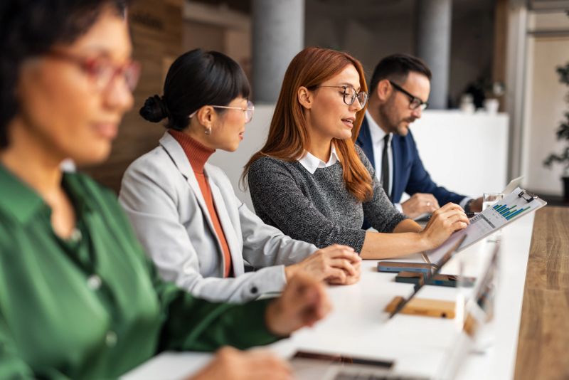 A group of professionals collaborating in a modern office setting, discussing business reports and strategies with focused engagement and cooperation.