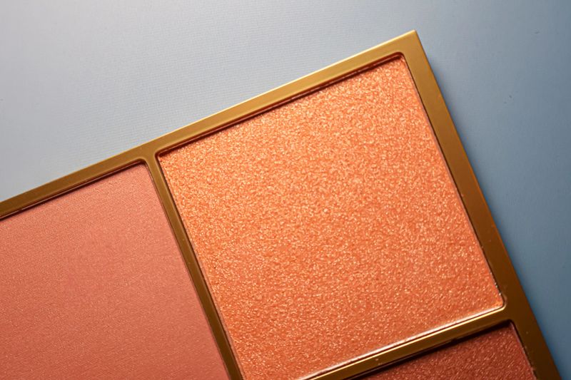 Makeup palette with a glittery shimmer eyeshadow and a matte blush in warm, peachy tones, creating a vibrant beauty product display