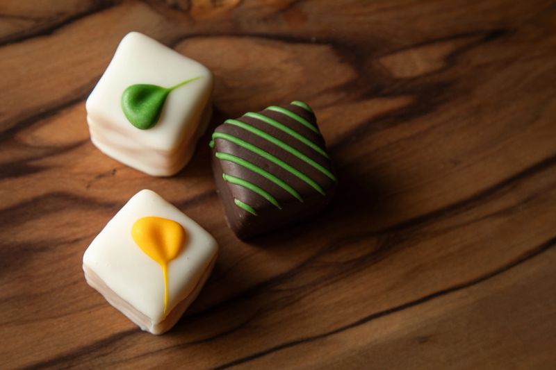 An elegant arrangement of artisan white chocolate squares, beautifully decorated and presented on a rustic wooden board. Perfect for gifts and celebrations.