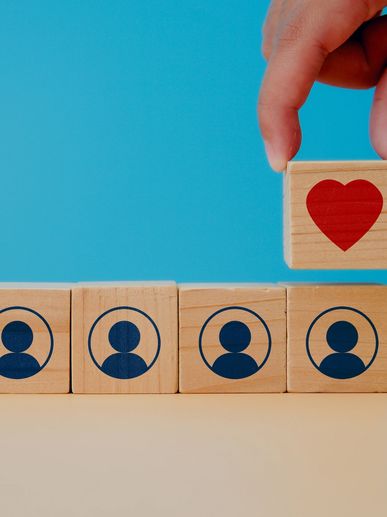 Hand placing a block with a red heart over blocks with user icons.