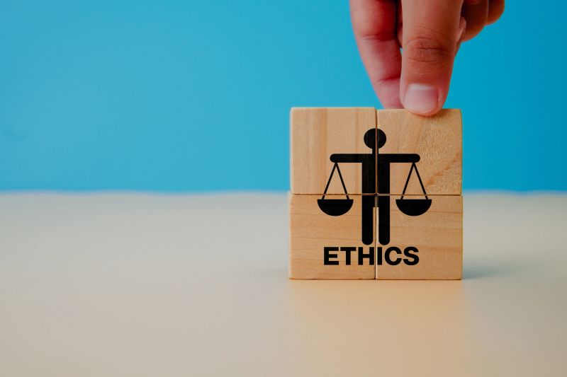Business ethics concept. Business moral principles concept.  Hand holds the wooden cubes with ETHICS symbols on grey background and copy space. Banner for business integrity, good governance policy.