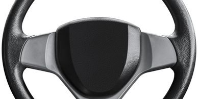 Close-up of a black car steering wheel with textured grips.