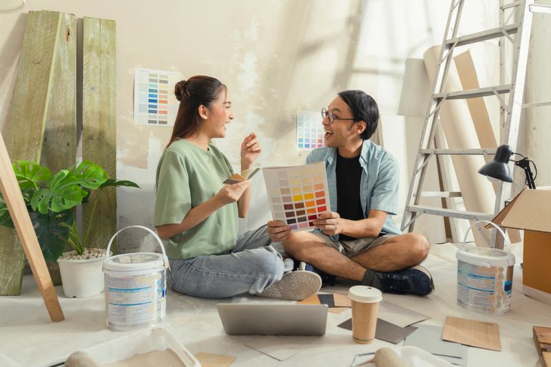 happy young couple collaborates on interior decor, choosing paint colors from a palette for their new home renovation, creating a beautiful, cozy space with teamwork and love.