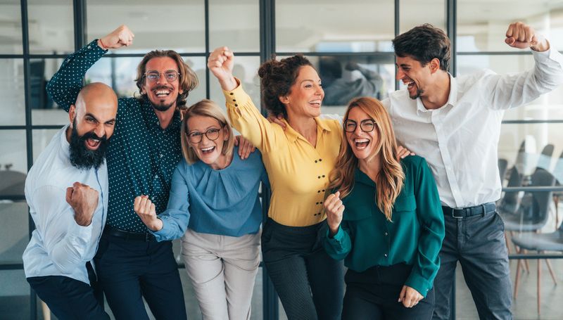 A joyful group of coworkers hugging and celebrating together in a modern office. Team members showing happiness, unity, and appreciation during a company celebration or team success event