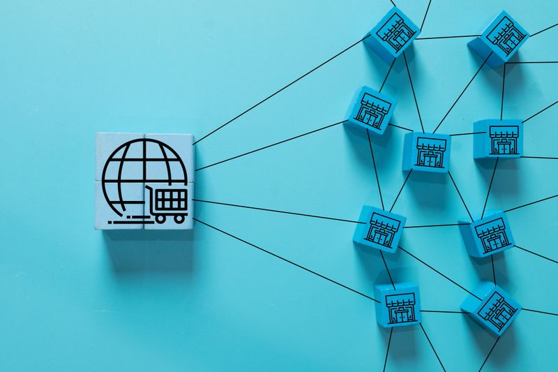 Blue blocks with store and globe icons connected by lines, representing e-commerce network, franchise business system, global online shopping, and logistics distribution.