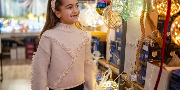 Smiling girl admiring decorative lights in a store.
