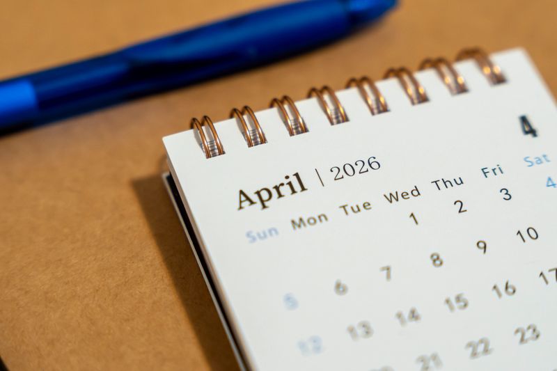 A close-up of a spiral-bound calendar page showing April 2026. Accompanying a blue pen, it signifies planning and organization for future appointments or events.