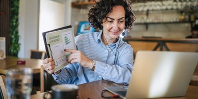 Woman presenting sales statistics during a video call in a cozy cafe.