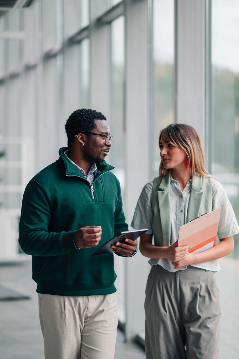 Business colleagues having a discussion while walking with a tablet and folder in a modern office building