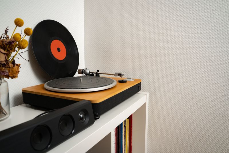 Vinyl record leaning against a wall next to a turntable in a simple home interior. Everyday music setup with minimal styling. Concept of music, audio, nostalgia, home, lifestyle.