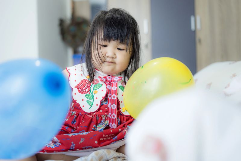 Cheerful toddler laughing while playing with colorful balloons