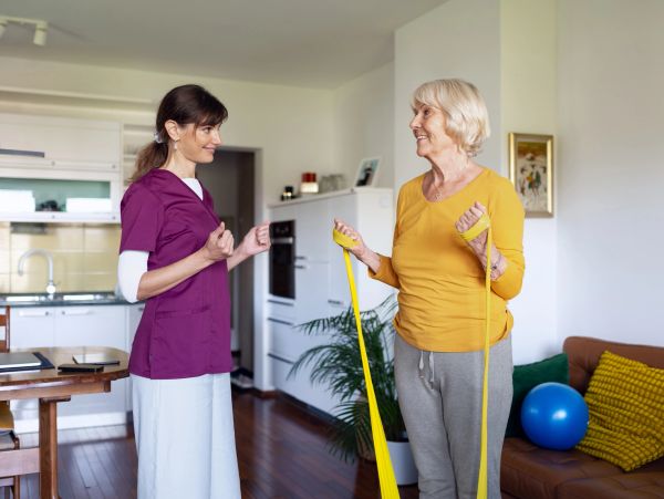 Two women exercising with resistance bands indoors.