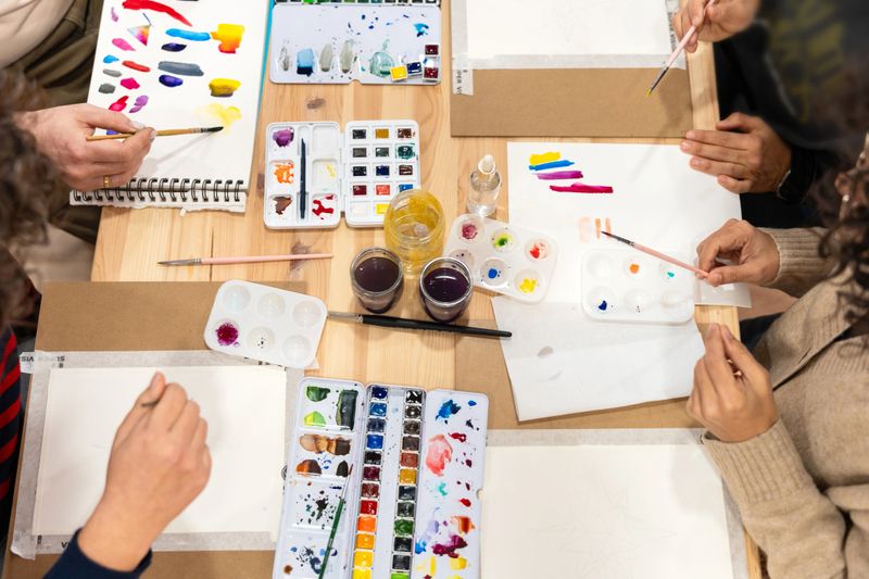 Group of people actively participating in a creative watercolor painting workshop, exploring new artistic skills