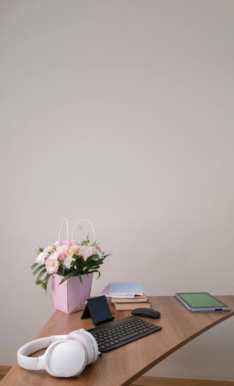 Clean modern office desk with tablet green screen, keyboard, mouse, and fresh bouquet of flowers, workspace mockup concept.