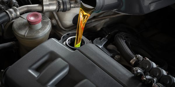 Golden engine oil being poured into a car engine.
