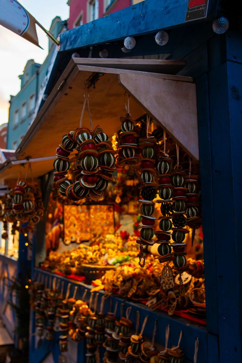 A market stall shows various handmade crafts hanging and displayed. The colorful items catch light during sunset. Gdansk, Poland