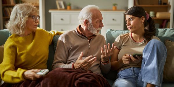 Three people having a serious conversation on a couch.