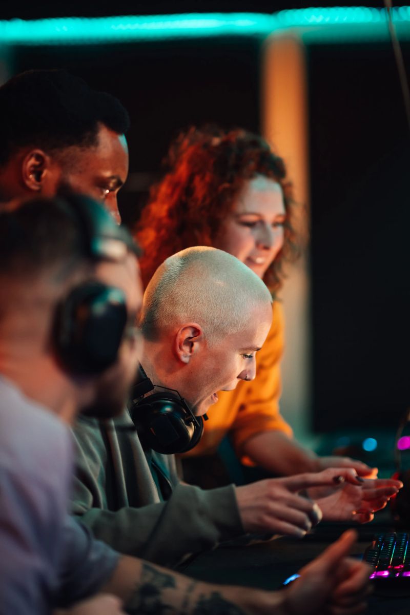 Young adult friends collaborating and celebrating a win during an online video game competition in a neon-lit gaming environment