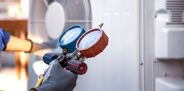 Technician using pressure gauges to check HVAC system.