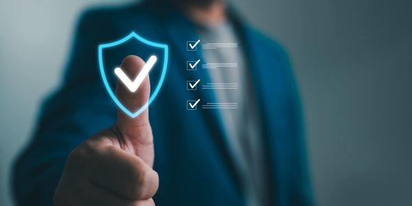 Person giving thumbs up with a digital shield and checklist symbolizing approval and security.