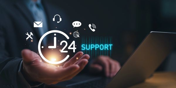 Businessman showcasing 24/7 customer support icons over laptop.