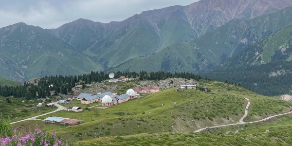 Research facility with domes in a green mountainous area under cloudy skies.