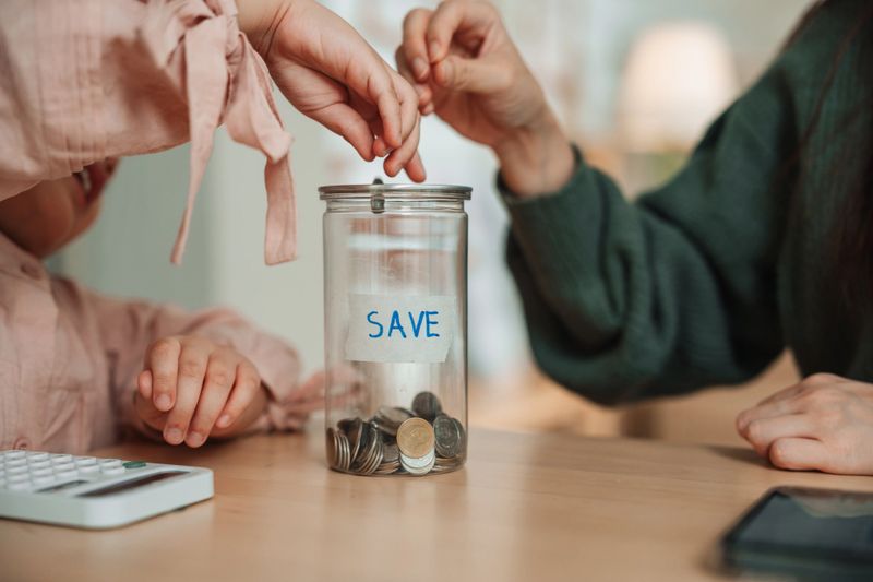 Mom teaching her daughter how to count coins and understand the value of saving, turning the moment into a fun and meaningful lesson about money and planning for the future