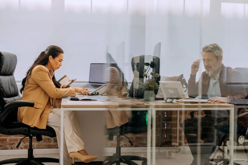Two colleagues working on desktop PCs at the office