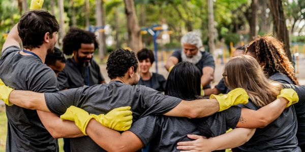 Group of volunteers in a circle wearing yellow gloves.