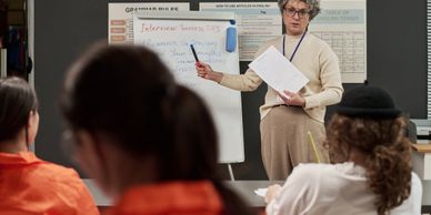 Teacher explaining in front of students in a classroom.