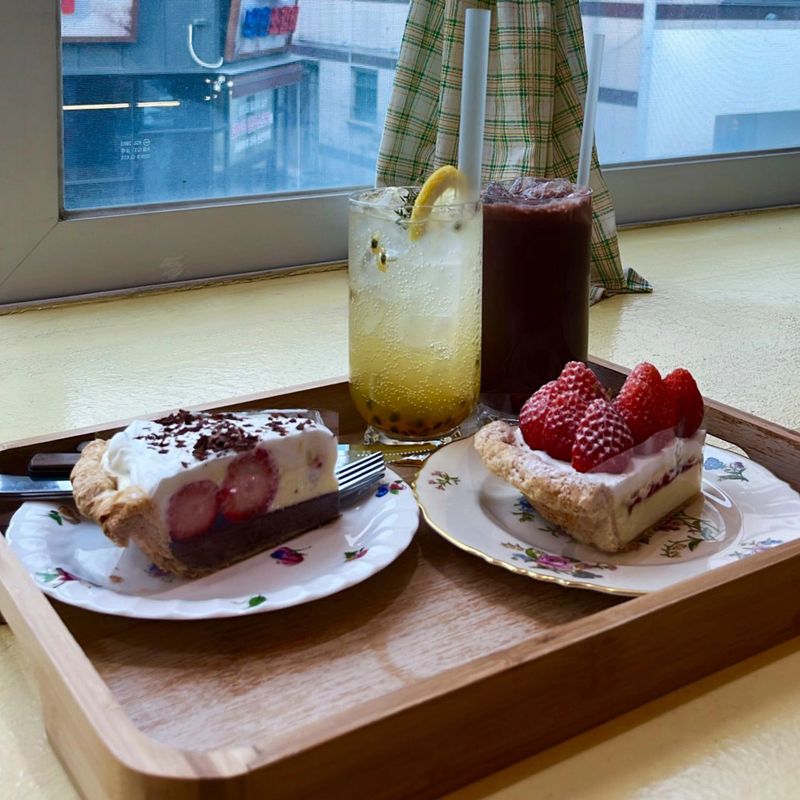 A delightful assortment of desserts displayed in a cozy cafe setting, featuring cakes, pastries, and sweet treats on elegant plates, creating a warm and inviting atmosphere.