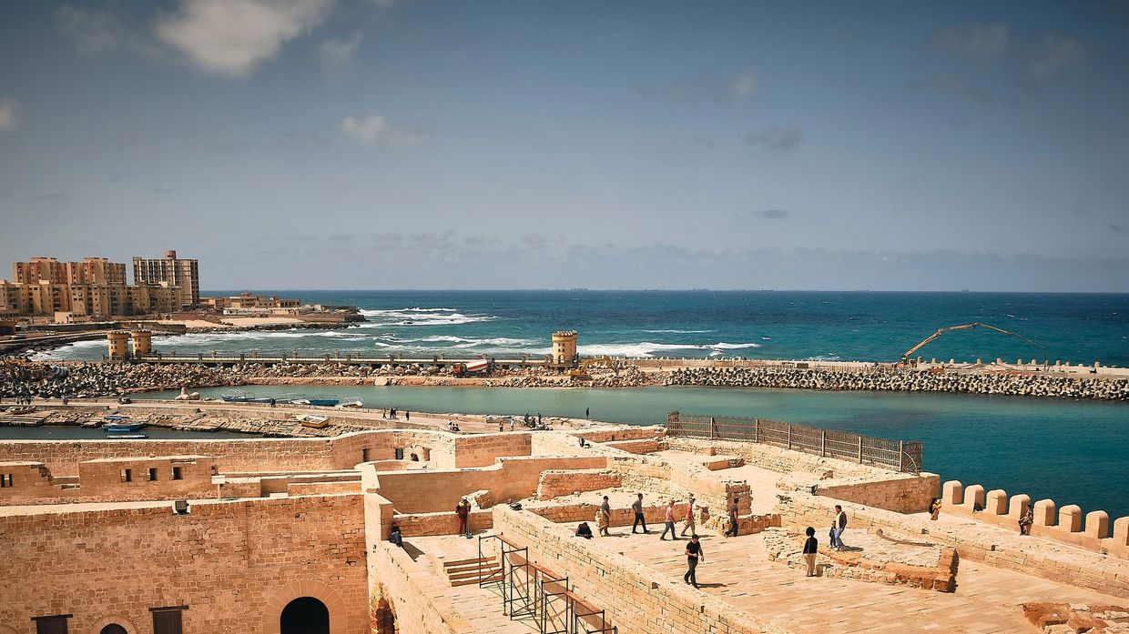 Historic seaside fortress with visitors enjoying the sunny day and ocean views.