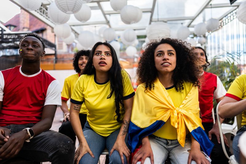 Friends cheering while watching a Colombia soccer match at the bar