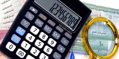 Calculator and magnifying glass on financial documents with Arabic text.