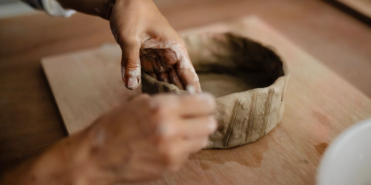 Hands shaping a clay pot in a pottery workshop.