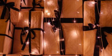 Wrapped gifts with black ribbons and fairy lights.