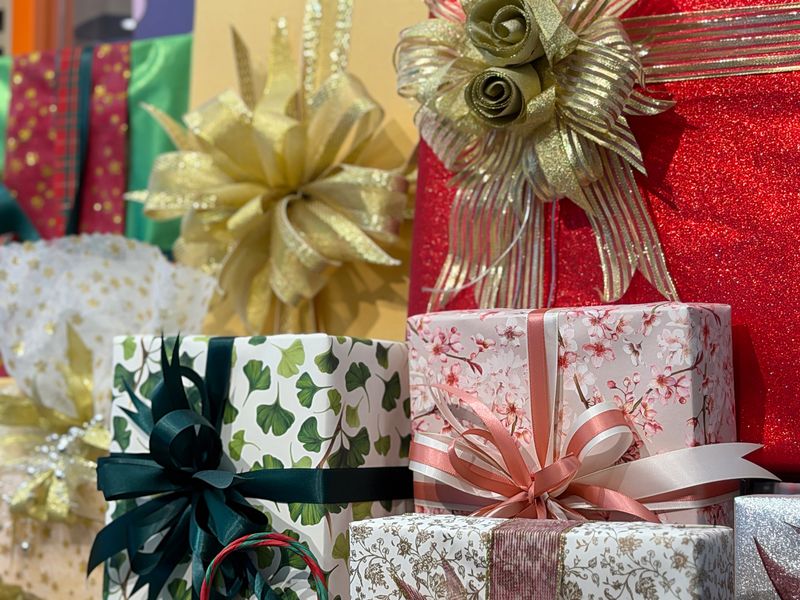 Stock photo shows a festive assortment of gift-wrapped presents and gift boxes adorned with colorful bows and ribbons, perfect for birthday and Christmas celebrations. The vibrant wrapping and elegant details create a joyful, cheerful atmosphere