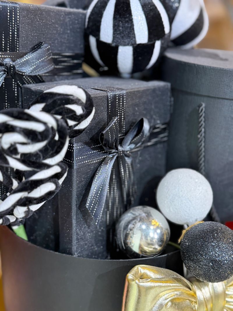 Stock photo shows a stylish Christmas presents wrapped in black and gold paper, adorned with coordinating baubles, creating a luxurious festive gift-wrapping scene. Perfect for holiday marketing, social media content, greeting cards, promotional materials, seasonal décor, and elegant celebrations.