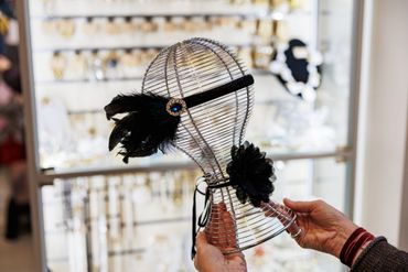 Vintage-style black feather headband on a wire mannequin head.