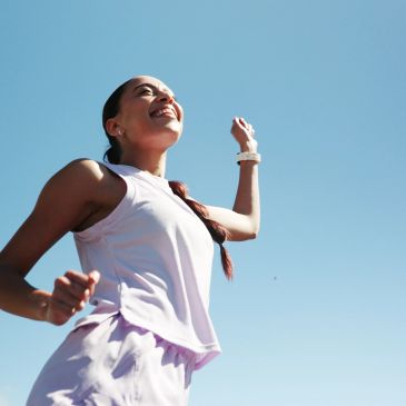 Woman jogging outdoors with a bright smile.