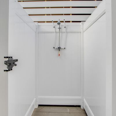 Minimalist outdoor shower with white panels and wall mount.