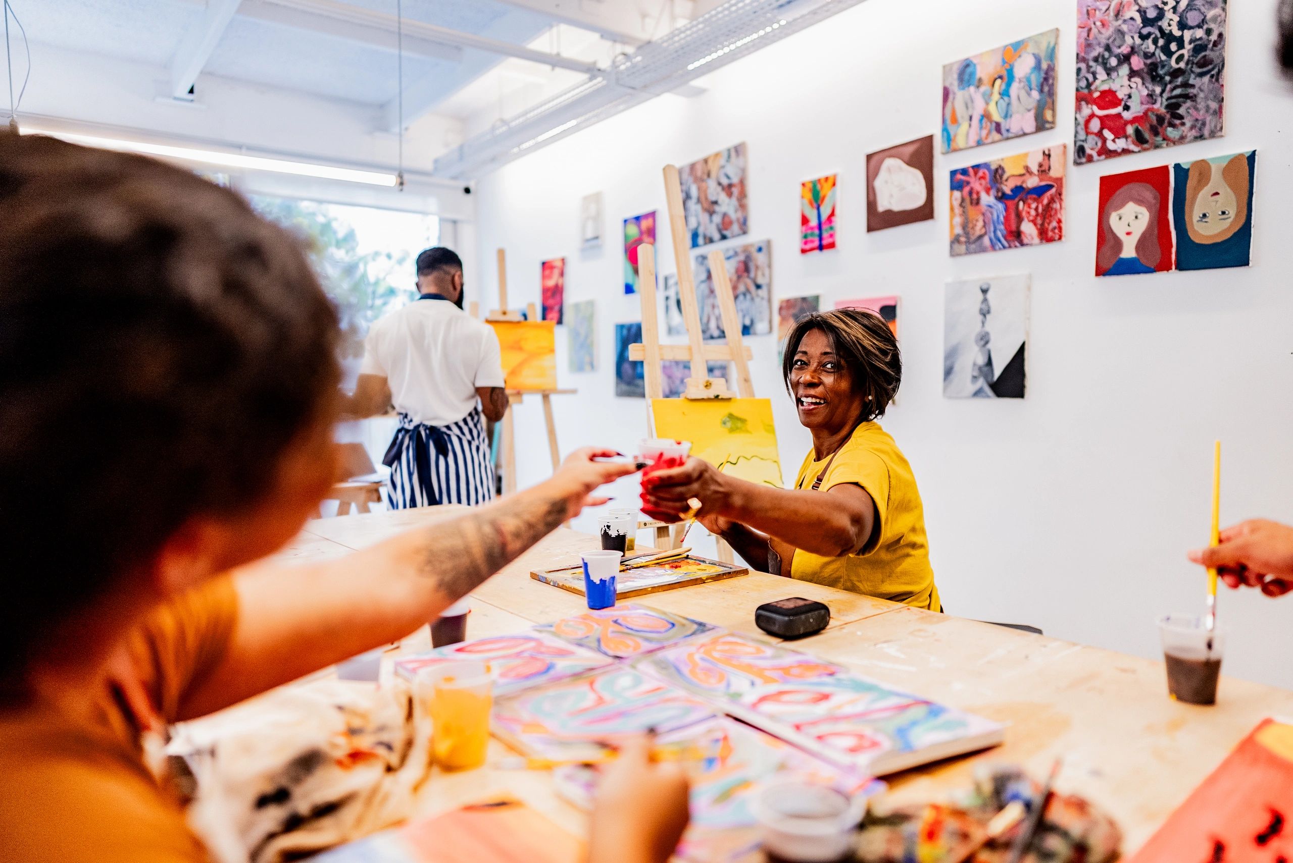 Two people sharing paint cups in an art studio.