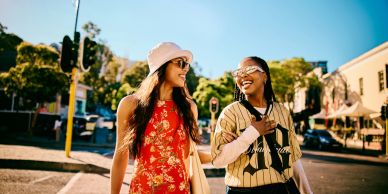 Two women smiling and walking outdoors.