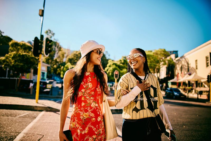 Two cheerful young women walking along a city street