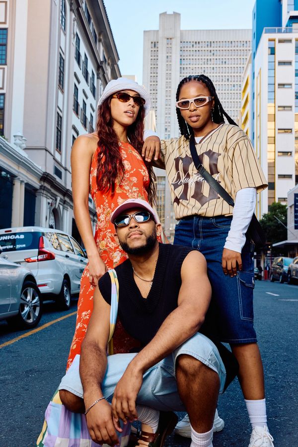 Three stylish friends posing confidently on a city street.