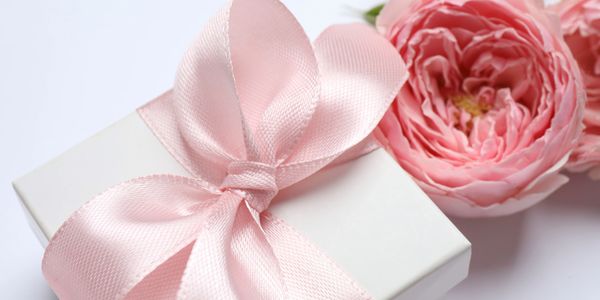 White gift box with a pink satin ribbon and pink roses.