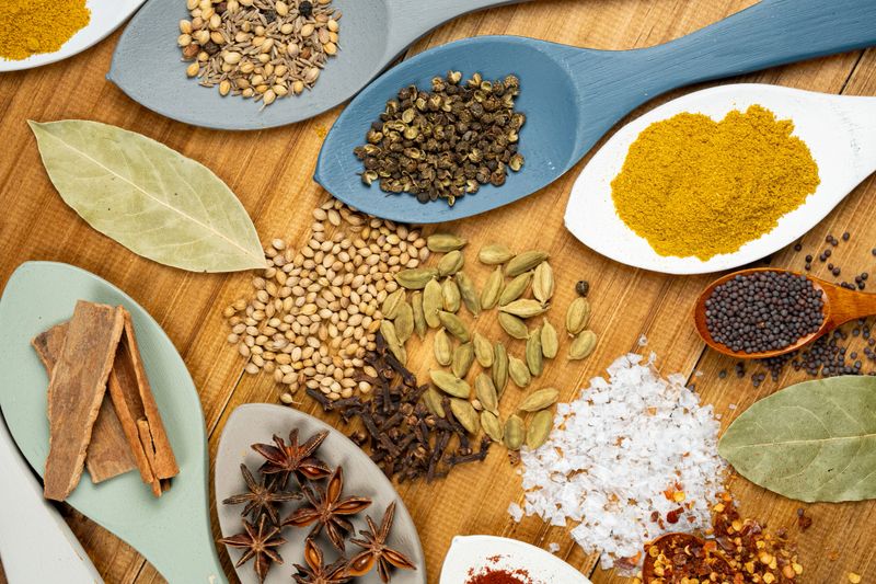 Various colorful spices and herbs arranged on a rustic wooden background, preparing delicious food and flavoring dishes